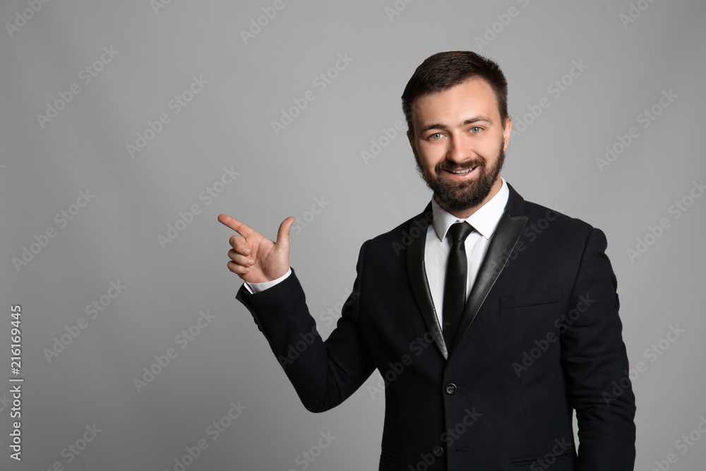Handsome businessman pointing at something on grey background Handsome businessman pointing at something on grey background