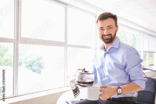 Handsome businessman drinking coffee in office