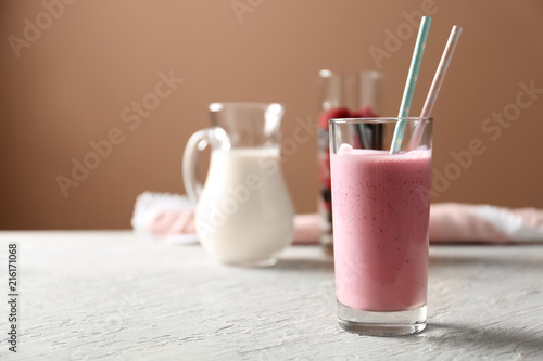 Glass with tasty raspberry milkshake on wooden table