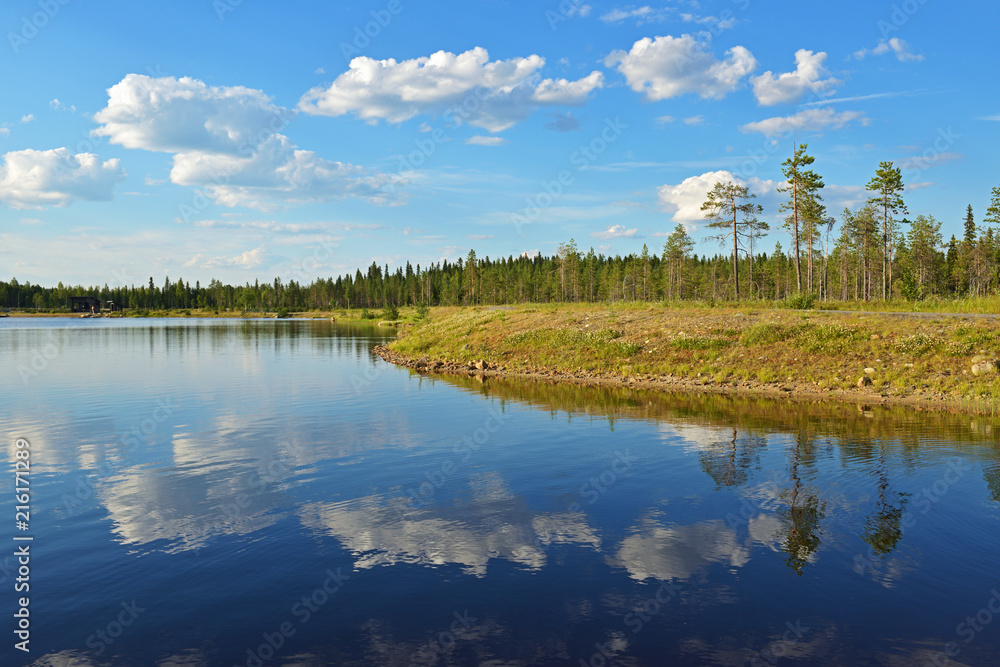 Reflection of clouds in northern forest lake. Summer landscape. Finnish Lapland
