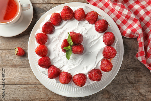 Delicious cake with strawberries on wooden table