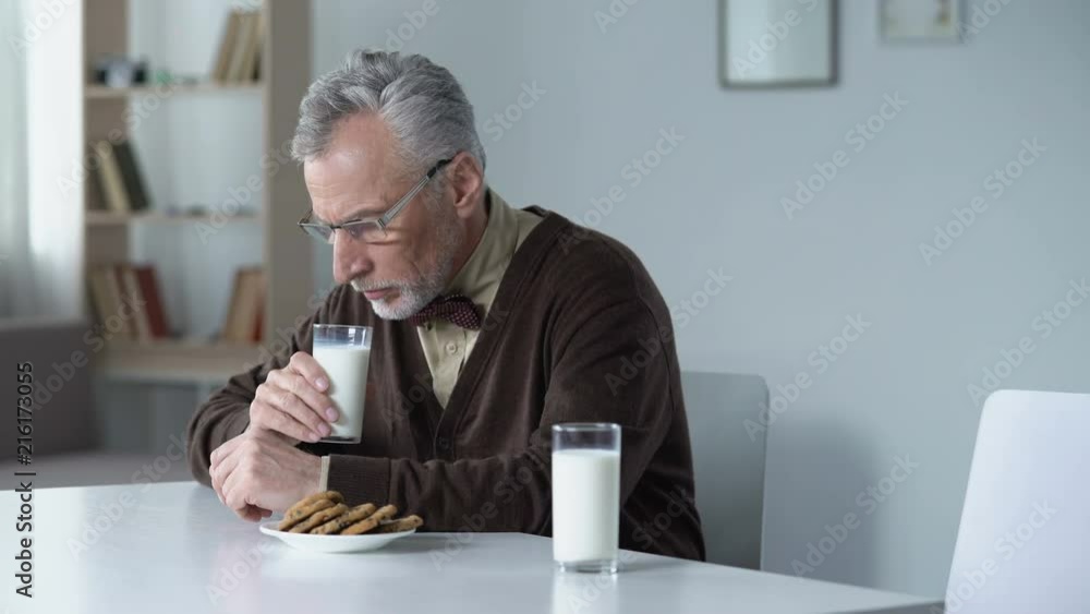 Sad grandfather lonely sitting at table with dinner for two, missing his family Sad grandfather lonely sitting at table with dinner for two, missing his family