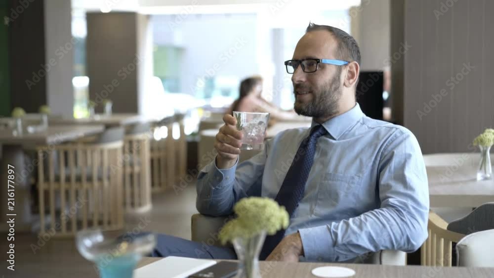 Happy man relaxing in the cafe and drinking water with ice
Happy man relaxing in the cafe and drinking water with ice