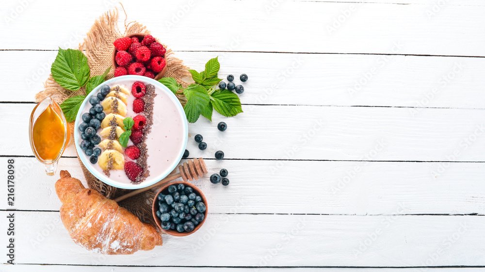 Yogurt with blueberries, raspberries and banana. In the plate. On a wooden background. Top view. Free space for text. Yogurt with blueberries, raspberries and banana. In the plate. On a wooden background. Top view. Free space for text.