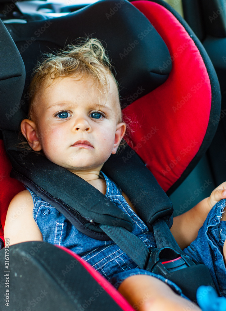 Portrait of cute baby boy sitting in car seat. Child