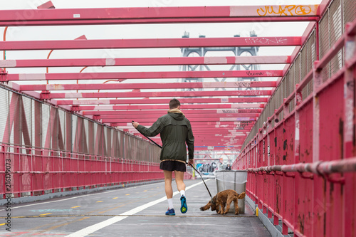 Unrecognizable sporty recreational male jogger with his dog on a leash at Williamsburg bridgein New York CIty, USA. photo