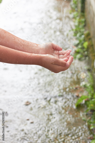 The child's hands catch raindrops. © valeriya