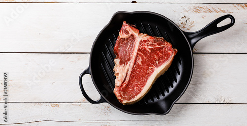 Raw fresh meat Hand selected Prime Dry Aging Steak T-bone in cast iron frying pan on wooden background copy space photo