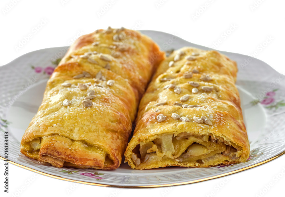 Apple strudel with cinnamon and sunflower seeds on a plate with a gilded edge. Selective focus. Apple strudel with cinnamon and sunflower seeds on a plate with a gilded edge. Selective focus.