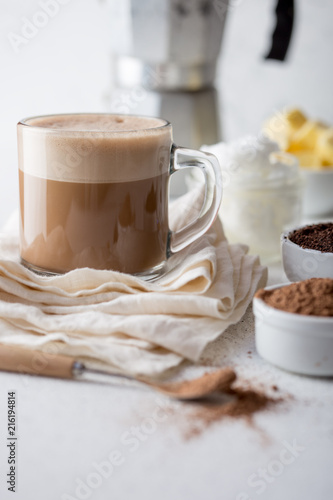 KETOGENIC KETO DIET DRINK. Coffe and cacao blended with coconut oil. Cup of bulletproof coffe with cacao and ingredients on white background