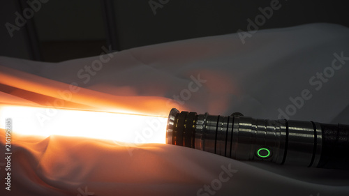 Fotografie Activated lightsaber resting on fabric