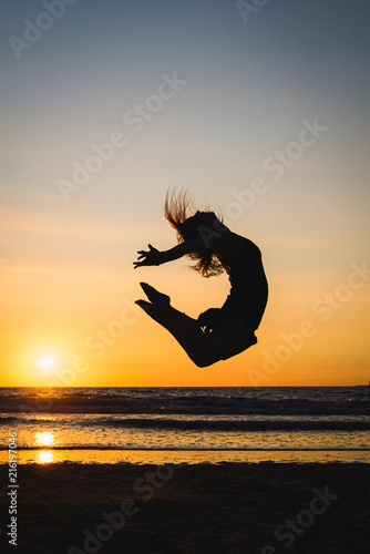Silhouette of a happy dancer girl jumping the sunset