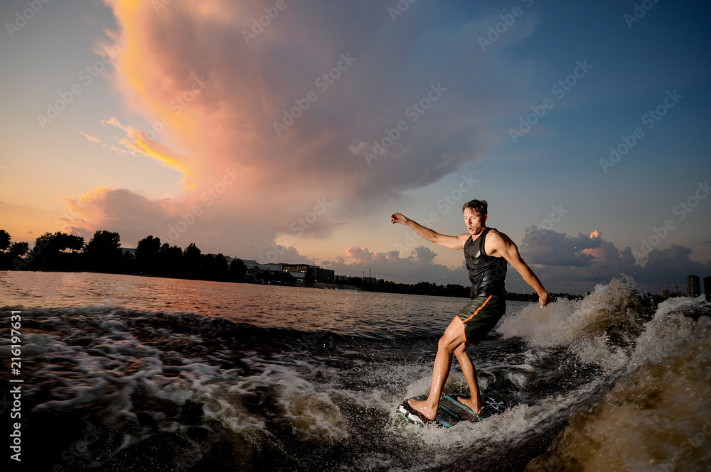 Active man riding on wakesurf down the river