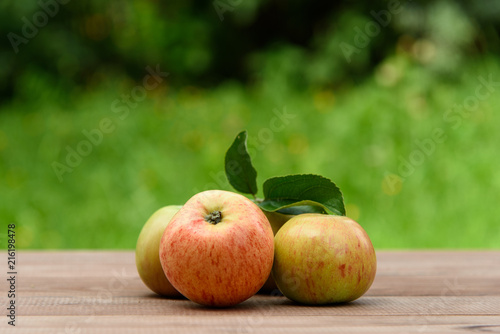 Juicy apples on a wooden table on a green background