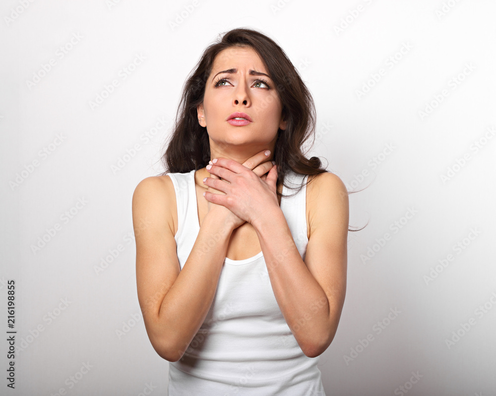 Suffering woman holding the throat with very strong pain and unhaapy face on white copy space background Suffering woman holding the throat with very strong pain and unhaapy face on white copy space background