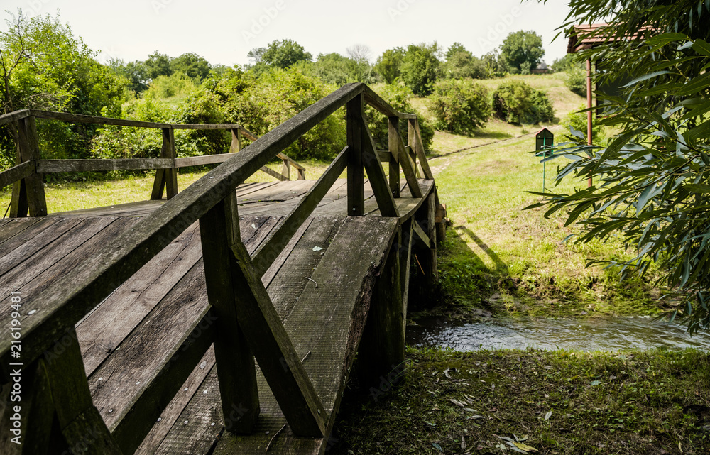Old oak wooden bridge and green meadow