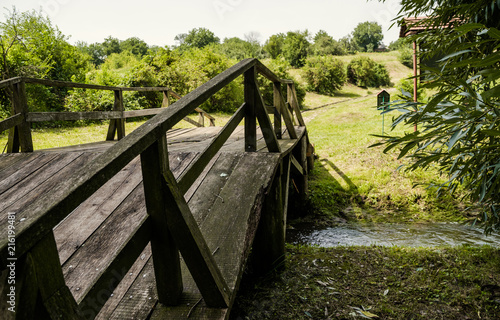 Old oak wooden bridge and green meadow