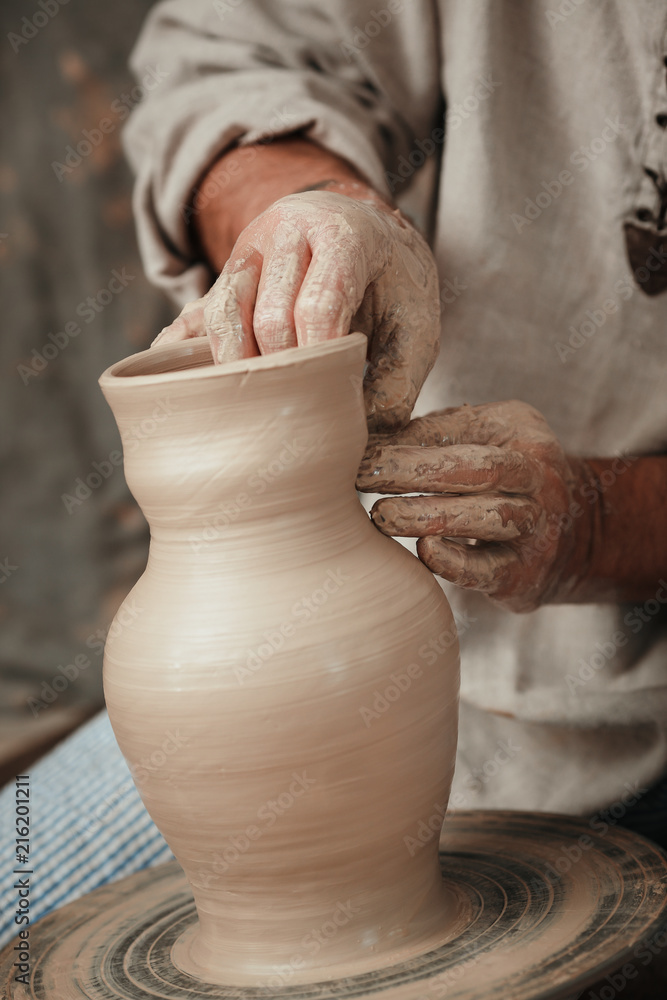 hands of a potter, creating an earthen jar on the circle 