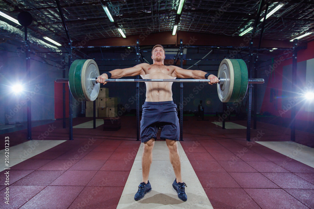 Fototapeta premium Muscular fitness man preparing to deadlift a barbell over his head in modern fitness center.Functional training.Snatch exercise.