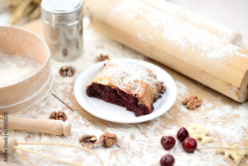 strudel (roll strudel) with cherry on a wooden board with flour photo