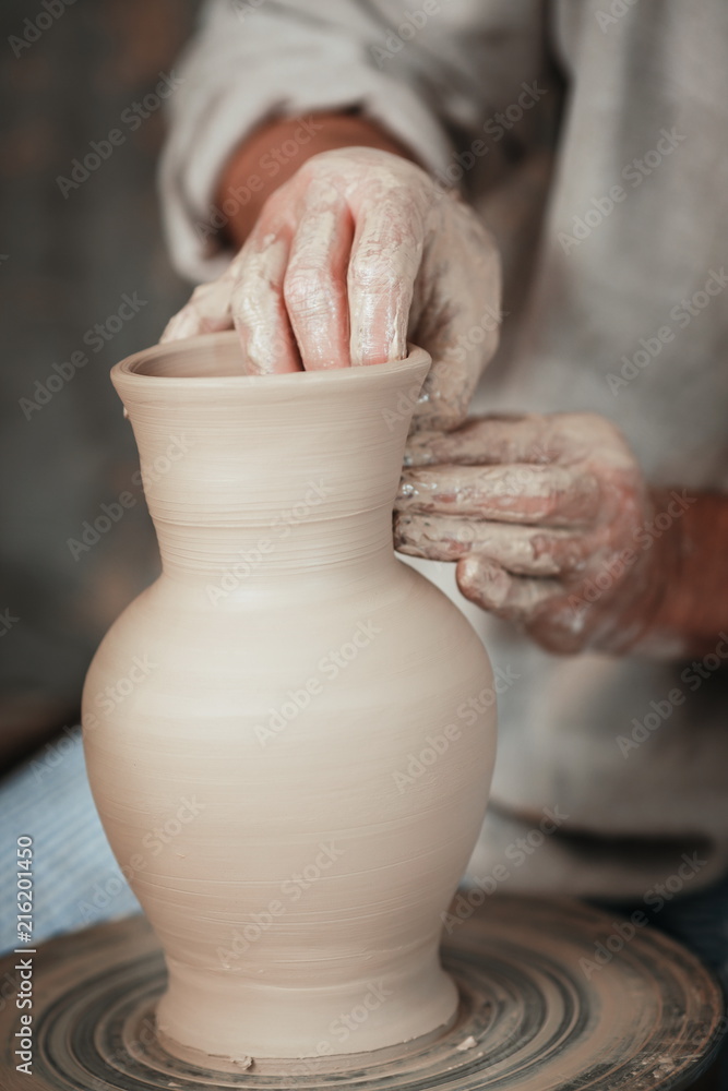 hands of a potter, creating an earthen jar on the circle 