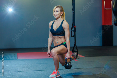 Sporty woman doing TRX and weight exercises in the gym