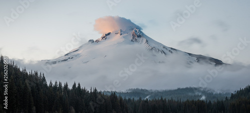 Mt Hood reflecting of Trillium lake at sunset. The last shards of light striking the clouds above its peek.