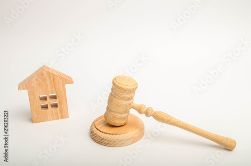 Wooden house and hammer of the judge on a white background. Concept trial property. The court decision on the transfer of property, the nationalization of property. The right to property photo