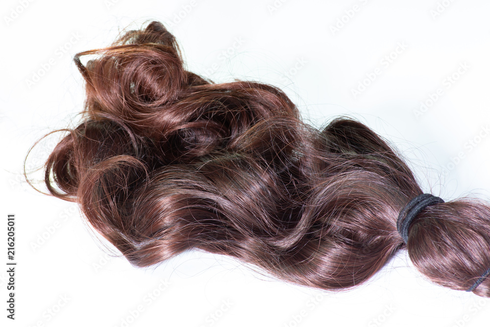 A set of hair extensions of reddish brunette curly hair on a beauty shop table A set of hair extensions of reddish brunette curly hair on a beauty shop table