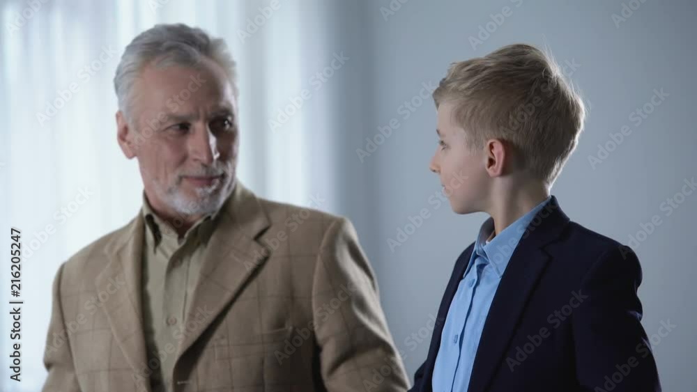 Cute grandfather and grandson putting jackets on, preparing for walk together Cute grandfather and grandson putting jackets on, preparing for walk together