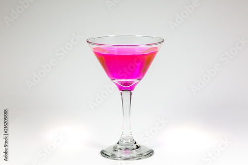 Halloween inspired Pink color cocktail in a clear glass sitting on a white table waiting to be enjoyed.