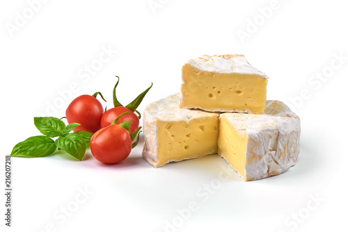 Round camembert cheese with a cut out piece and cherry tomatoes, isolated on white background.
