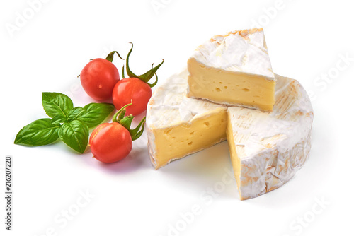 Round camembert cheese with a cut out piece and cherry tomatoes, isolated on white background.