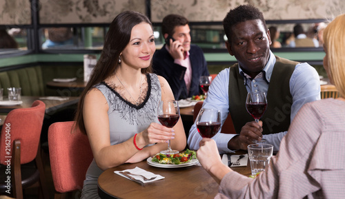 Happy couple with female friend in restaurant