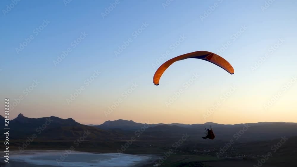 Close-up: paraglider is flying over the edge of the hill against the background of the sea Close-up: paraglider is flying over the edge of the hill against the background of the sea