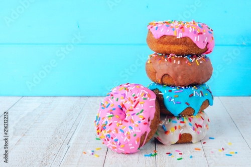 Stack of donuts with pastel colored icing on a soft blue background