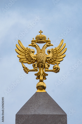 Golden Russian coat of arms on a blue sky background. Coat of arms of Russia is the official state symbol of the Russian Federation and Russian Empire in history.