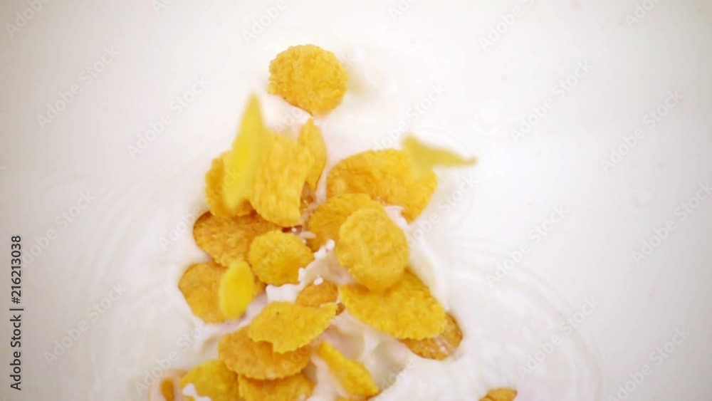 Cornflakes falling and sink into the milk. Corn flakes in slow motion. Cornflakes falling and sink into the milk. Corn flakes in slow motion.