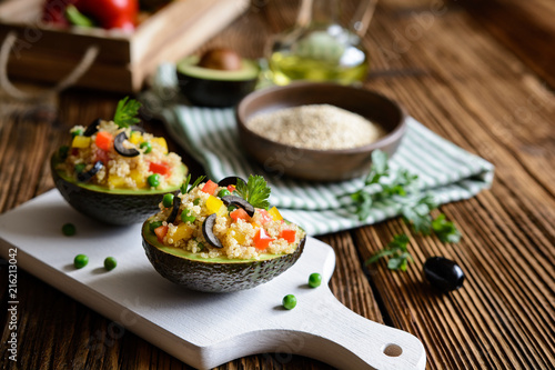 Avocado stuffed with quinoa, green peas, tomato, olives, bell pepper and parsley photo