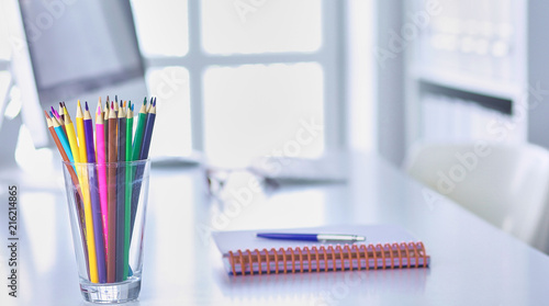 Graphite pencils in a glass grid-container on the office table.