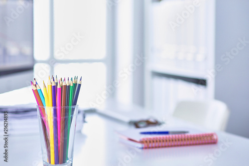 Graphite pencils in a glass grid-container on the office table.