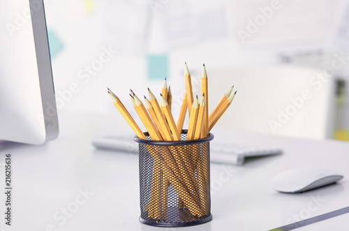 Graphite pencils in a metal grid-container on the office table.