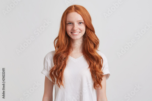 Fotografiet Portrait of cheerful beautiful young woman with long wavy red hair and freckles
