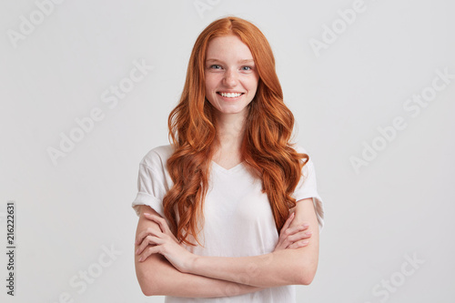 Billede på lærred Closeup of happy confident young woman with long wavy red hair and freckles wear