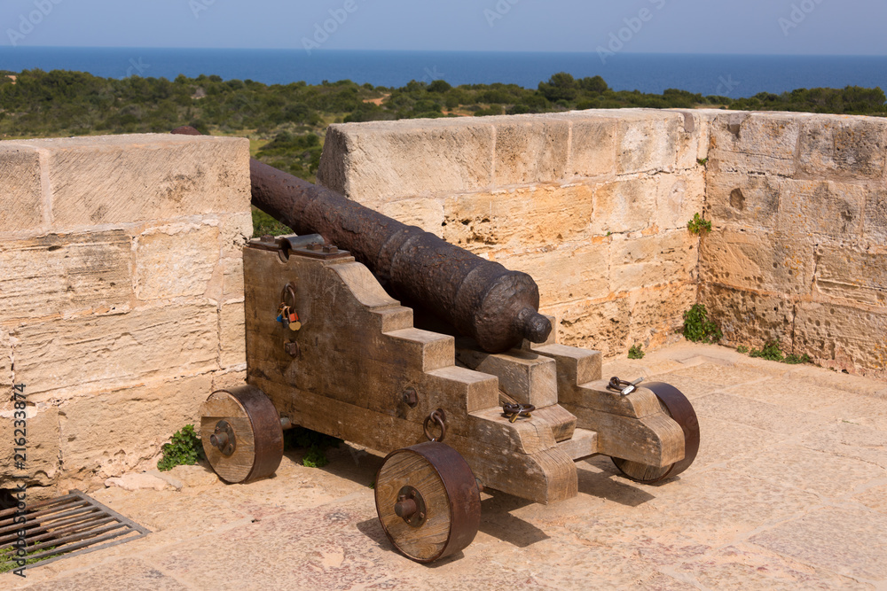 Old antique iron cannon on the old defence tower of Punta de N'Amer near Sa Coma, on the Spanish Balearic Mediterranean island of Mallorca Old antique iron cannon on the old defence tower of Punta de N'Amer near Sa Coma, on the Spanish Balearic Mediterranean island of Mallorca