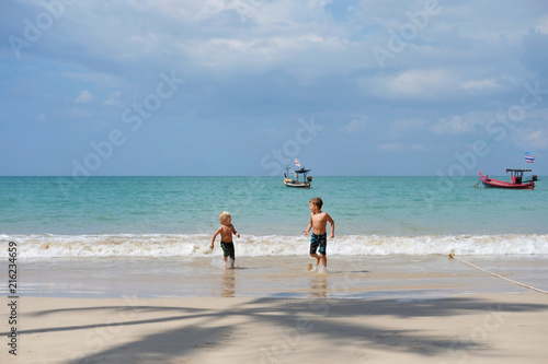 Wallpaper Mural Two brothers boys playing on beach, run away from waves Torontodigital.ca