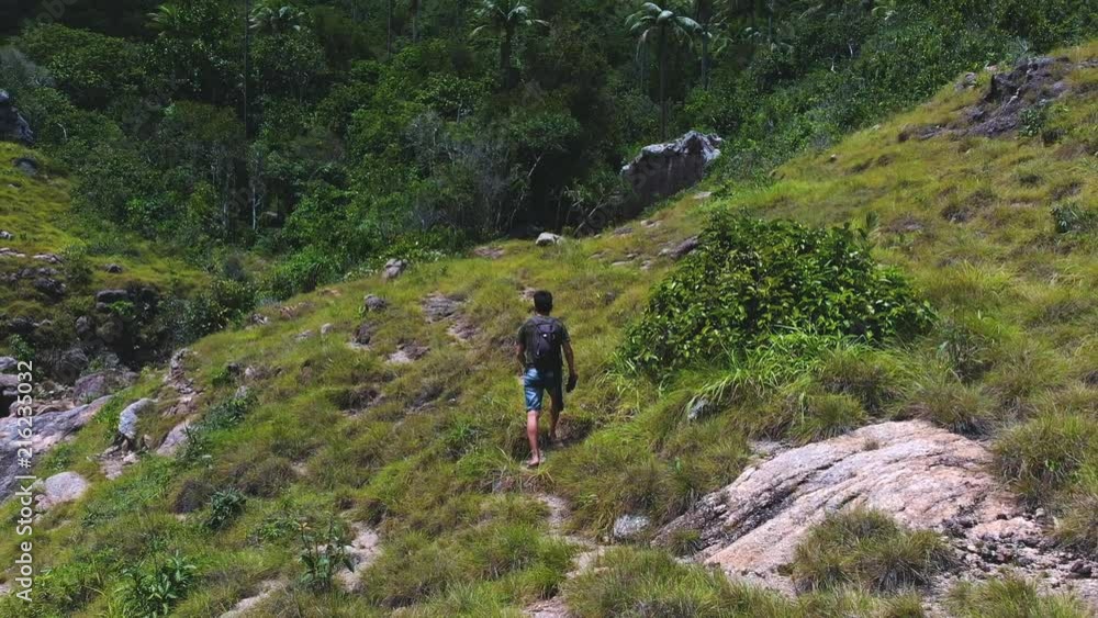 Hiker man trekking walking with backpack in trail at day time in mountains. Traveler man walking on the hill Hiker man trekking walking with backpack in trail at day time in mountains. Traveler man walking on the hill