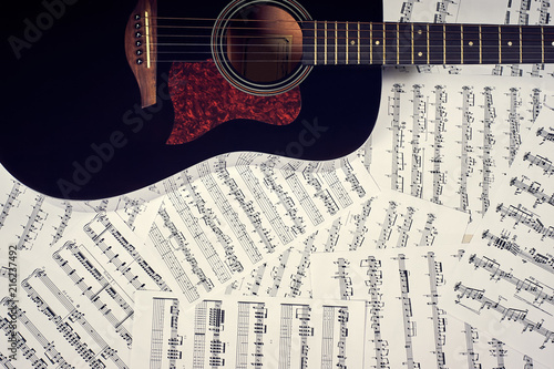 dark acoustic guitar on a background sheet notes, close-up