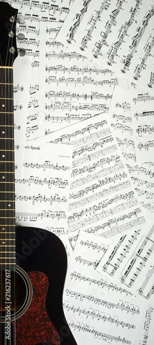 dark acoustic guitar on a background sheet notes, close-up