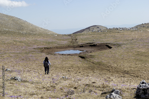 girl hiker in mountain summit and small lake